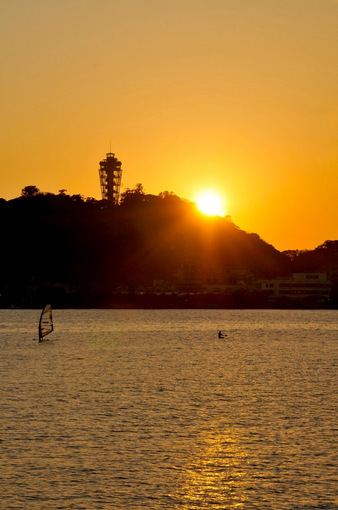 腰越漁港から片瀬東浜越しの江ノ島の夕日とパドルサーフィン